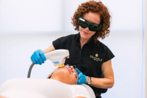 An Erasable Med Spa provider wearing blue gloves slowly moves the BBL HEROic handpiece across a patient's skin to address unwanted pigment and redness during skin toning in Tampa.