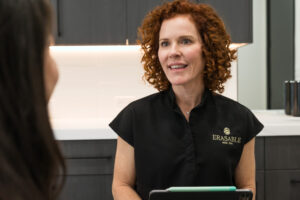 An Erasable Med Spa provider, wearing black scrubs, listens as a female patient discusses her sexual dysfunction. Together, they can create a customized treatment strategy to improve her sexual health in Tampa.