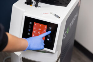 An Erasable Med Spa provider, wearing blue gloves, adjusts the settings for our Juliet vaginal rejuvenation laser. For patients searching 